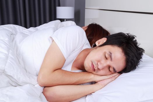 young man sleeping with his wife in a comfortable bed at home