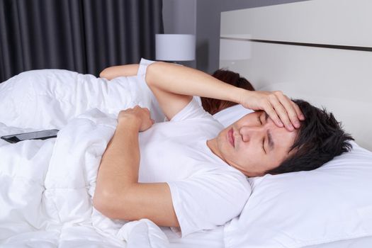 man having sleepless on bed and having migraine,stress, insomnia, hangover in the bedroom