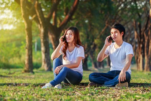 young couple talking on mobile phone in the park