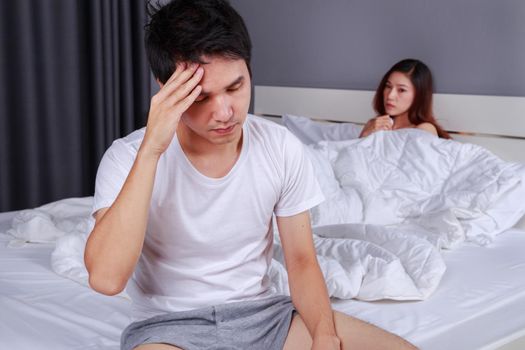 upset man having problem sitting on the bed with his wife in the bedroom
