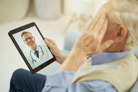 Senior citizen holding tablet and chatting online with a therapist while holding a weight