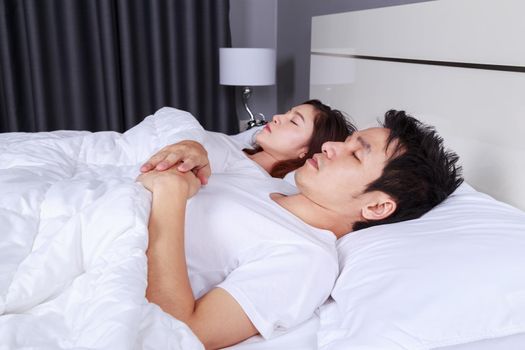 young couple sleeping on a comfortable bed in bedroom at home