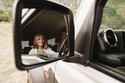 Beautiful young smiling couple sitting on front passenger seats and driving a car