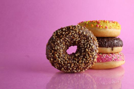 Sweet still life donut berliner close-up at the back lie a stack of three doughnut yellow on a bright pink background copyspace