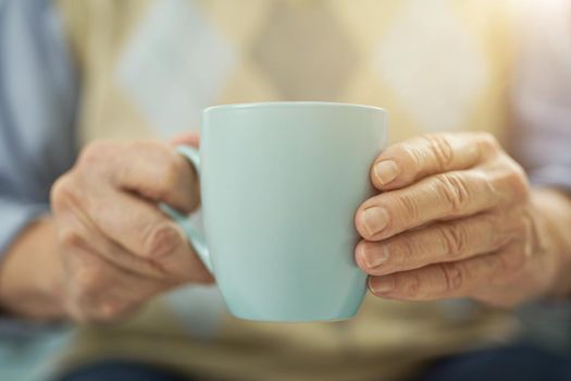 Close up of male hands holding cup of tea while sitting at home. Copy space. Lifestyle concept