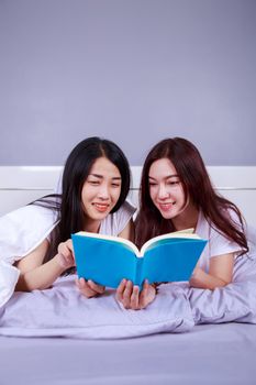 two woman reading a book on bed in the bedroom