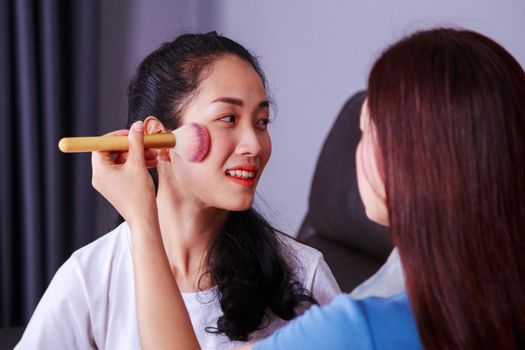 young woman using brush makeup on face her friend