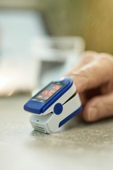 Cropped photo of elderly person hand with fingertip pulse oximeter clipped on