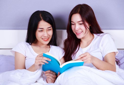 two woman reading a book on bed in the bedroom