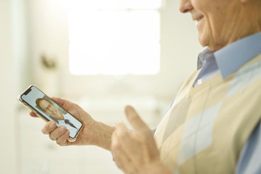 Cropped photo of a senior gentleman showing thumbs up to his doctor while consulting him on video-call