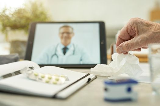 Cropped photo of eldelry man hand getting a paper tissue from a table with tablet and medical notes