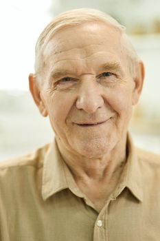 Close-up photo of gladsome elderly citizen smiling and looking at the camera