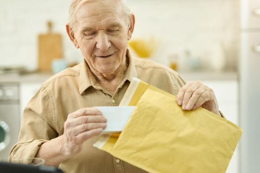 Copy space photo of an aged man taking a little box out out of a yellow manila envelope