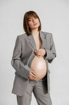 pretty caucasian pregnant female with short hair in grey suit, picture isolated on white background