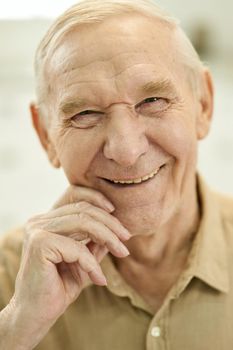 Close-up portrait photo of a cheerful senior man laughing and looking at the camera