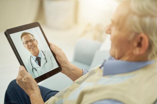 Senior man holding tablet and chatting online with a therapist while looking on the screen