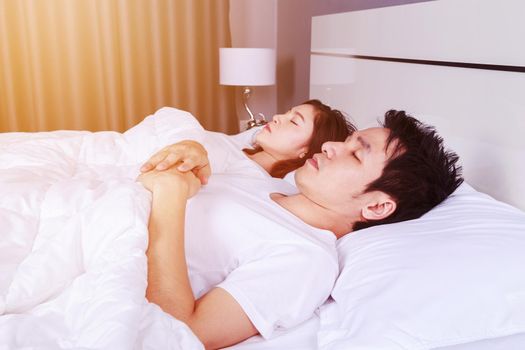 young couple sleeping on a comfortable bed in bedroom at home