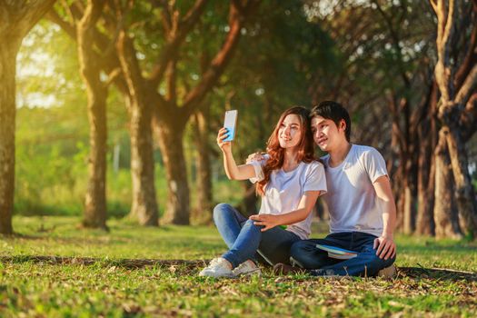 young couple using mobile phone taking a selfie in the park