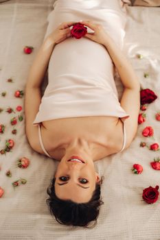 Pregnant woman holds red rose near belly as symbol of new life, wellbeing, fertility, unborn baby health. Pregnancy, maternity, gynecology. High quality photo