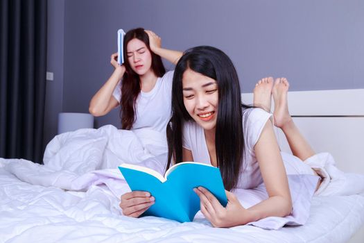 two woman reading a book on bed in the bedroom