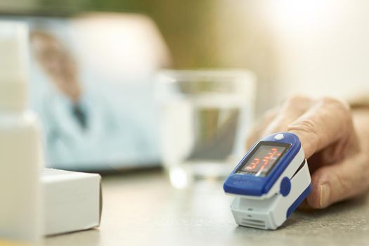 Selective focus photo of a hand with a fingertip medical device with digital tablet in the background