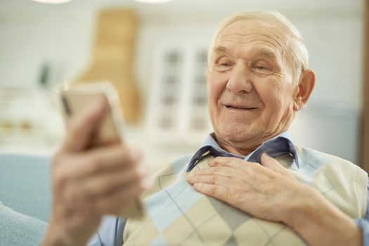 Happy old-aged man enjoying the conversation on the phone online at home