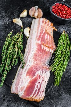 Raw sliced pork bacon ready for cooking. Black background. Top view.