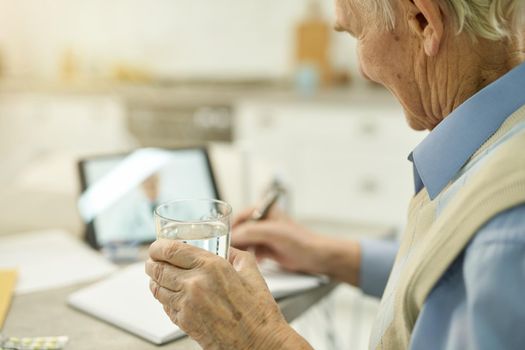 Cropped photo of senior gentleman with glass of water listening to medical advice on an online consultation