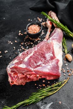 Raw goat leg with salt and garlic. Farm meat. Black background. Top view.