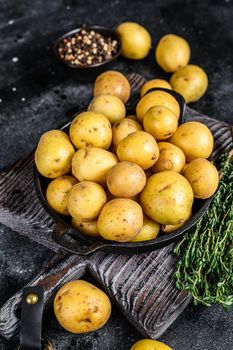 Young whole mini Potatoes in a pan. Black background. Top view.