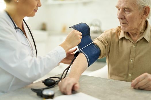 Cropped photo of a senior man having his blood pressure checked by a female doctor with manometer