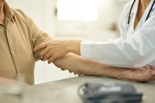 Fragment photo of medical worker in white uniform rolling up the sleeve of eldelry gentleman