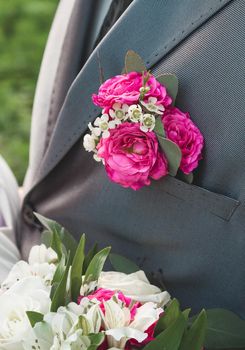 Pink rose boutonniere on the groom's grey suit, close-up, wedding element of the man's decor.