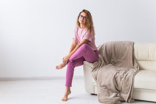 Young attractive woman dressed in beautiful colorful pajama posing as a model in her living room. Comfortable sleepwear, home relaxation and female fashion concept