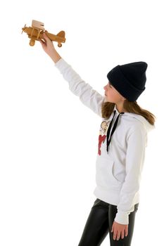 Happy little girl is playing with a wooden plane in the studio on a white background. The concept of emotions and children's games. Isolated.