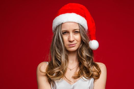 Portrait of unhappy young woman posing in studio and looking at camera, isolated on red background. Party concept. Copy space