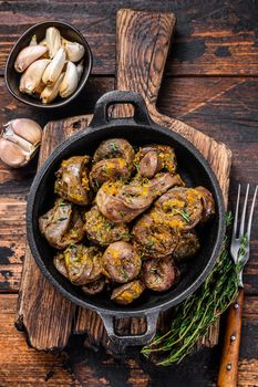 Cooked turkey hearts offals with herbs. Dark wooden background. Top view.