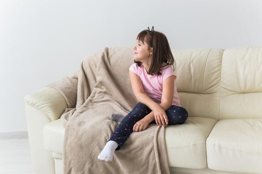 Cute girl kid with cat ears sitting on the couch. Children and childhood.