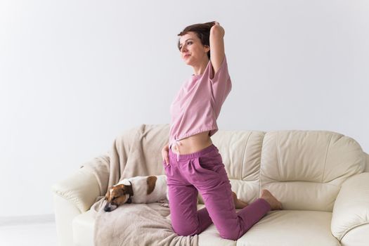 Young attractive woman dressed in beautiful colorful pajama posing as a model in her living room. Comfortable sleepwear, home relaxation and female fashion concept