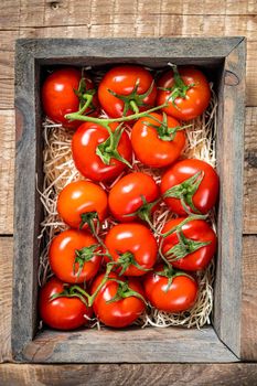 Ripe Red tomatoes in wooden market box. Wooden background. Top view.