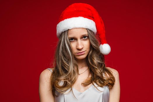 Portrait of unhappy young woman posing in studio and looking at camera, isolated on red background. Party concept. Copy space