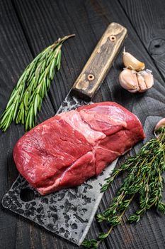 Raw lamb meat fillet steak on a cleaver. Black wooden background. Top view.