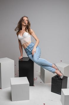 Pretty young woman lying on black boxes, isolated on grey background. Copy space. Lifestyle concept