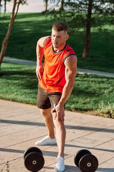 sporty man in the morning in the park with dumbbells exercise. High quality photo