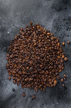 Roasted coffee beans on rustic table. Black background. Top view.