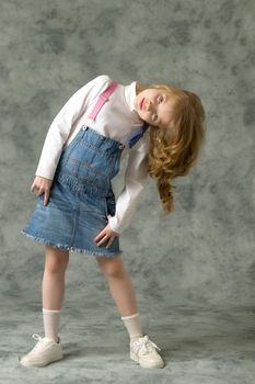 Beautiful little girl in a short denim dress. Concept of beauty and fashion, happy childhood.