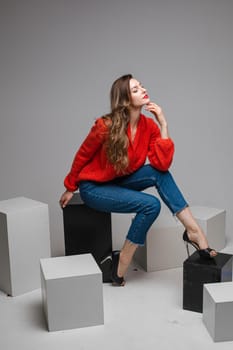 beautiuful caucasian woman sits on a white cubes and looks to the camera, picture isolated on white background