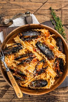 Mussels and clams Mafaldine pasta with tomato sauce in a rustic wooden plate. Wooden background. Top view.