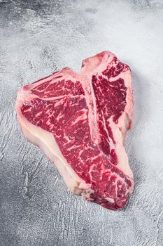 Raw T-bone or porterhouse Steak on kitchen table. White background. Top view.