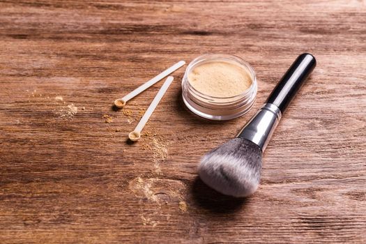 Mineral powder of different colors with spoon dispenser for make-up on wooden background.